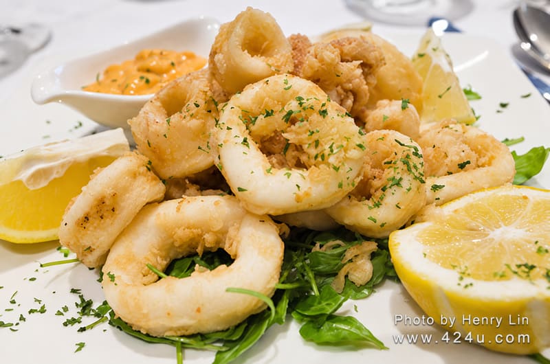 Fried calamari rings with lemon wedges and a dipping sauce