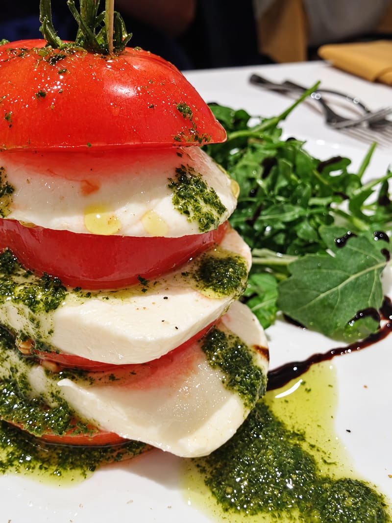 Tomato and mozzarella stacked with pesto, greens and a balsamic drizzle