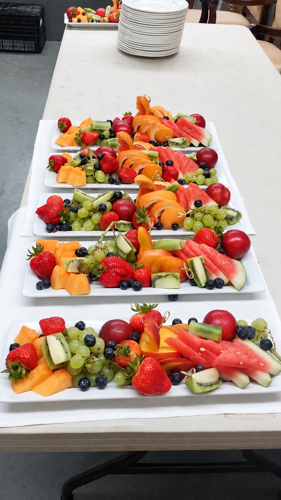 Long platters of fresh cut fruit lined up on a table