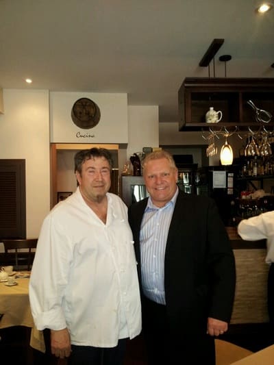 Two men smiling for a photo inside the restaurant, by the bar