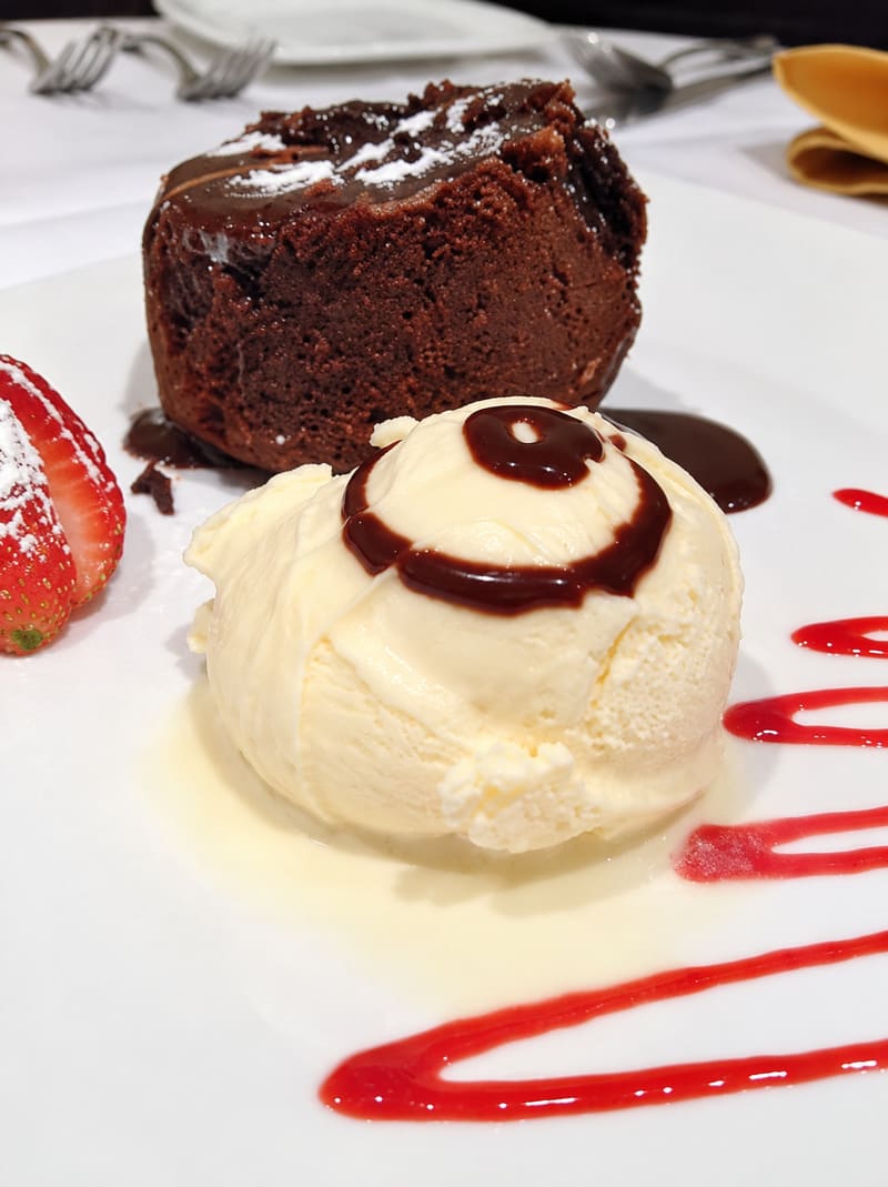 Chocolate cake and a scoop of vanilla ice cream with raspberry sauce