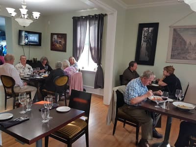 Guests at their tables in a dining room with pale green walls and framed pictures