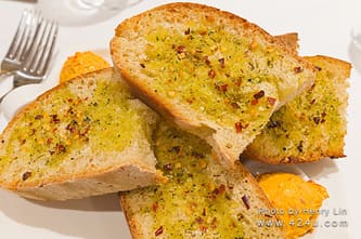 Thick slices of garlic bread on a white plate with an orange spread