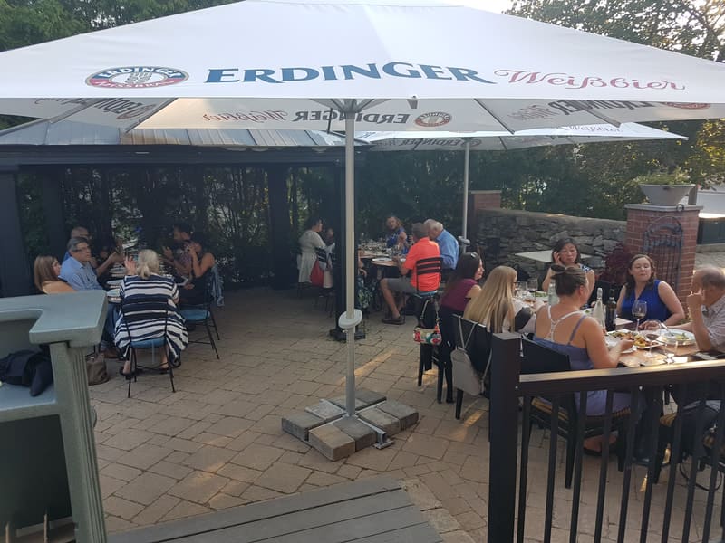 Guests at tables under large white umbrellas on a stone patio
