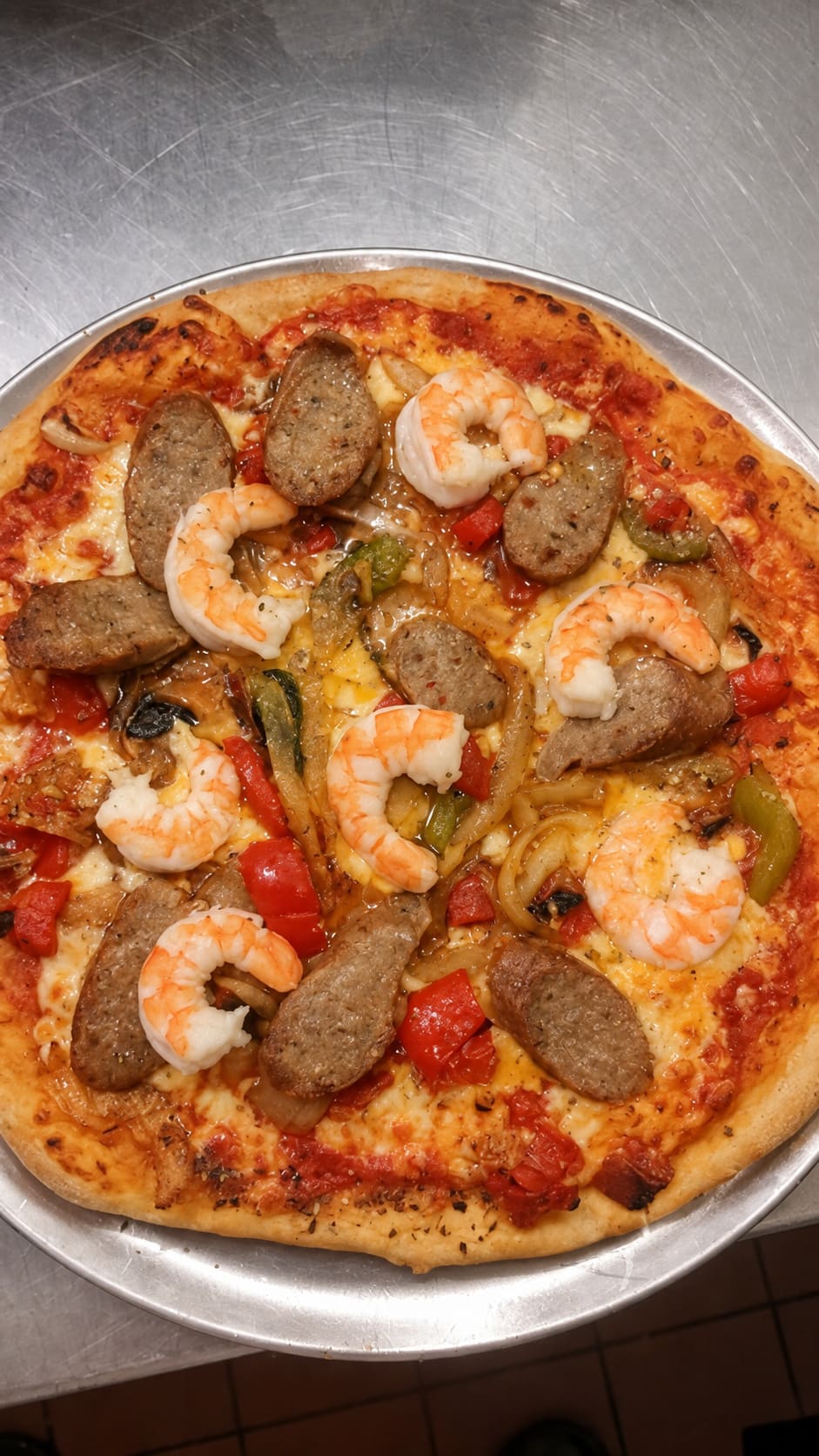 A pizza topped with shrimp and sausage on a metal tray