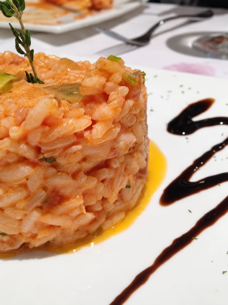 A neat round of tomato risotto with a herb sprig and a balsamic swirl